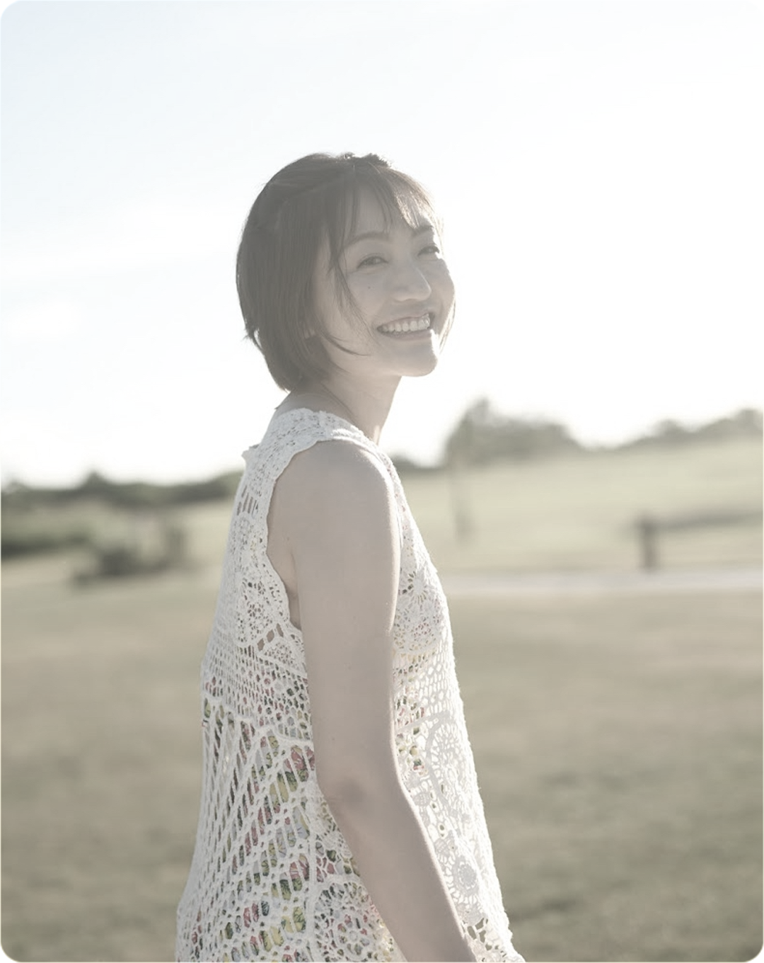 芝生の上で笑顔の女性のモノクロ写真